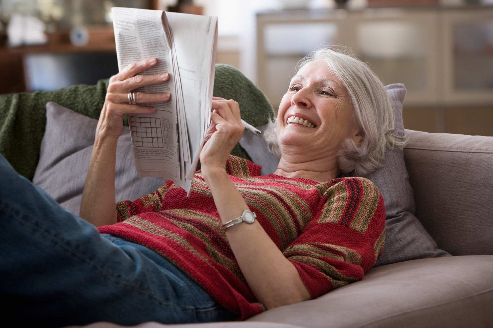 Woman doing crossword on the couch.